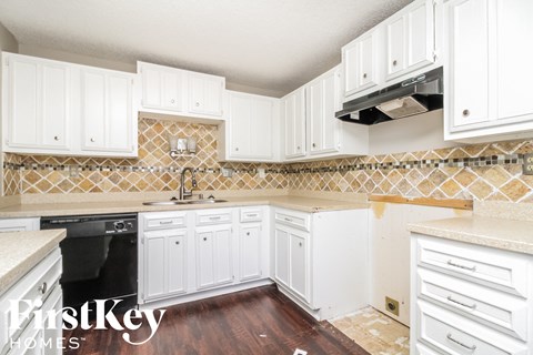 A kitchen under renovation with white cabinets and a tile backsplash.