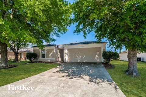 a beige house with a garage and trees