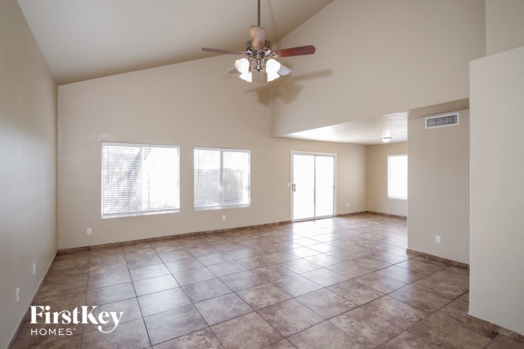 an empty living room with a ceiling fan and tiled floors