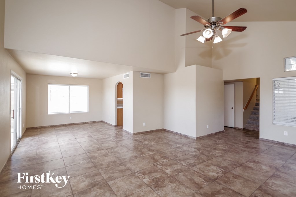 an empty living room with a ceiling fan and a tile floor