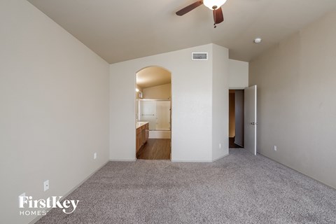 a spacious living room with carpet and a ceiling fan