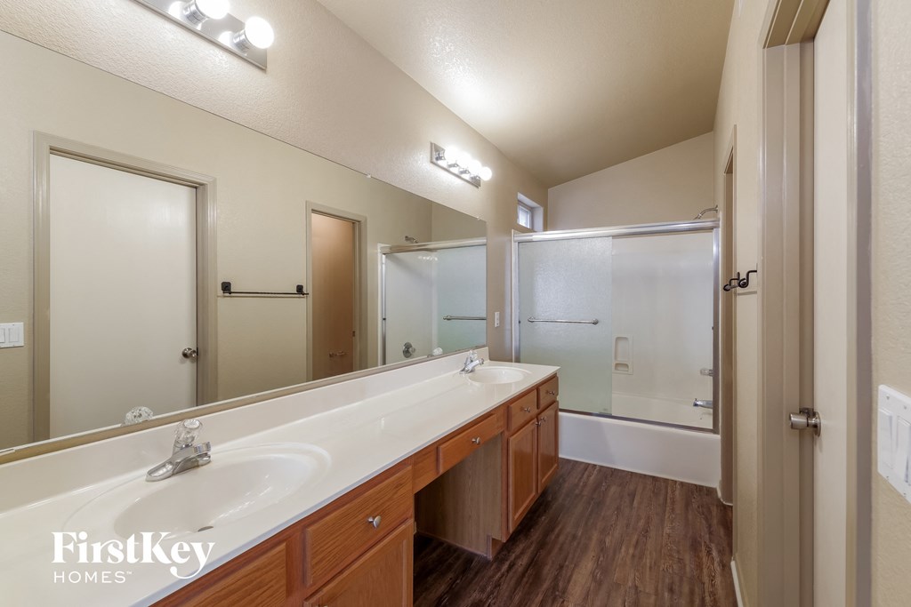 the master bathroom has a large vanity with a large mirror and a shower