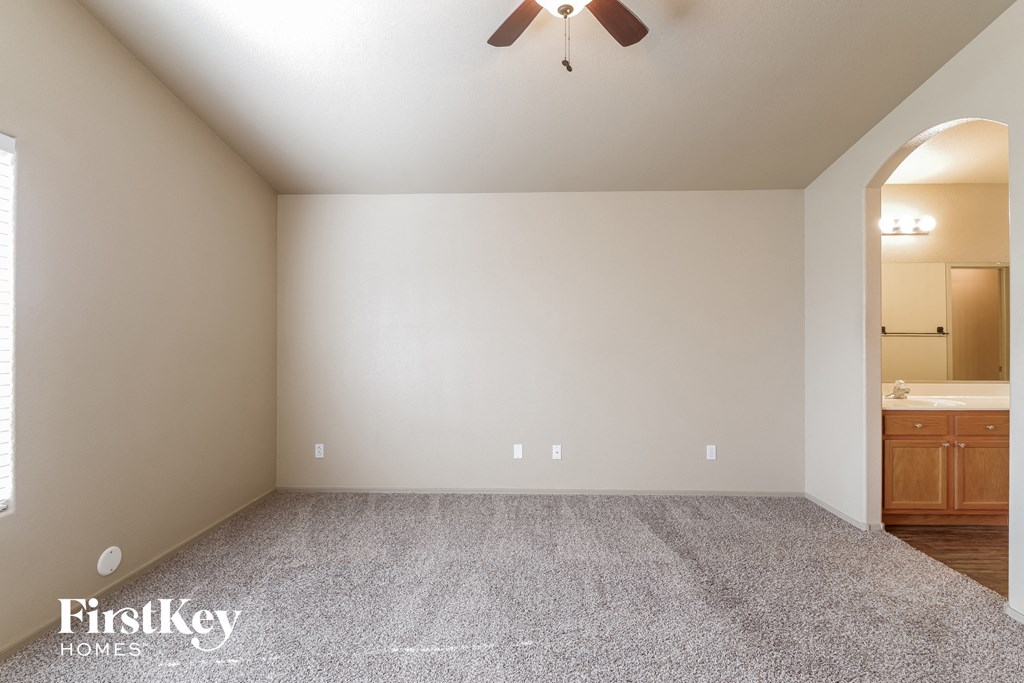 the living room of an empty house with carpet and a ceiling fan