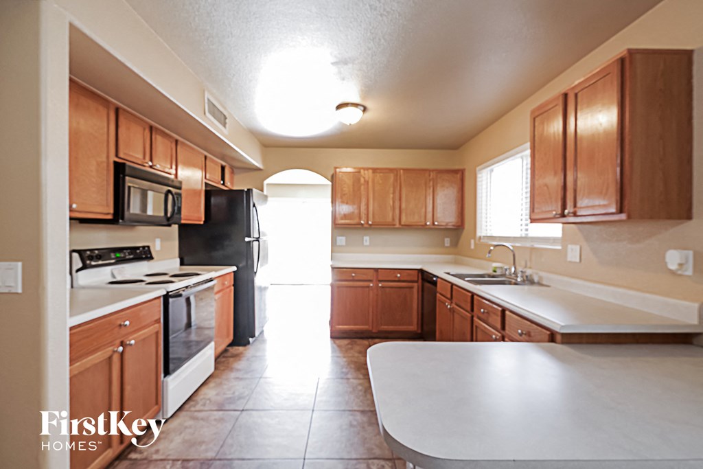a kitchen with wooden cabinets and white counters and black appliances
