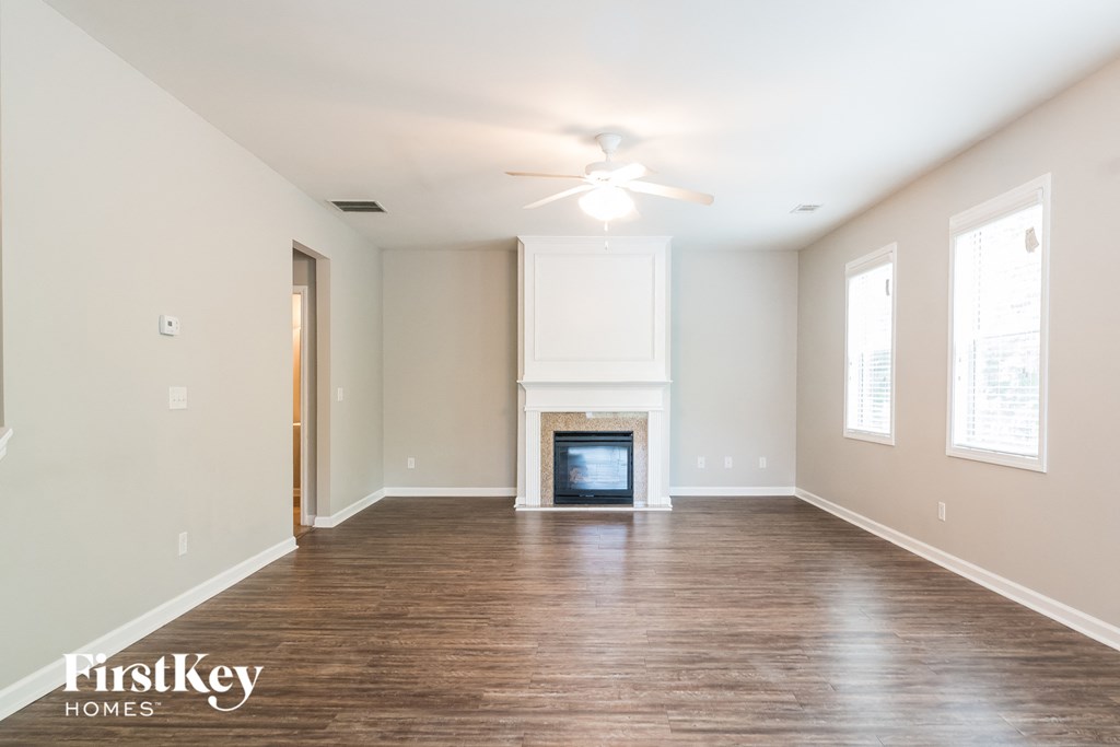 an empty living room with a fireplace and a ceiling fan