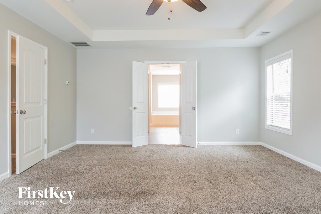 a bedroom with a carpeted floor and a ceiling fan