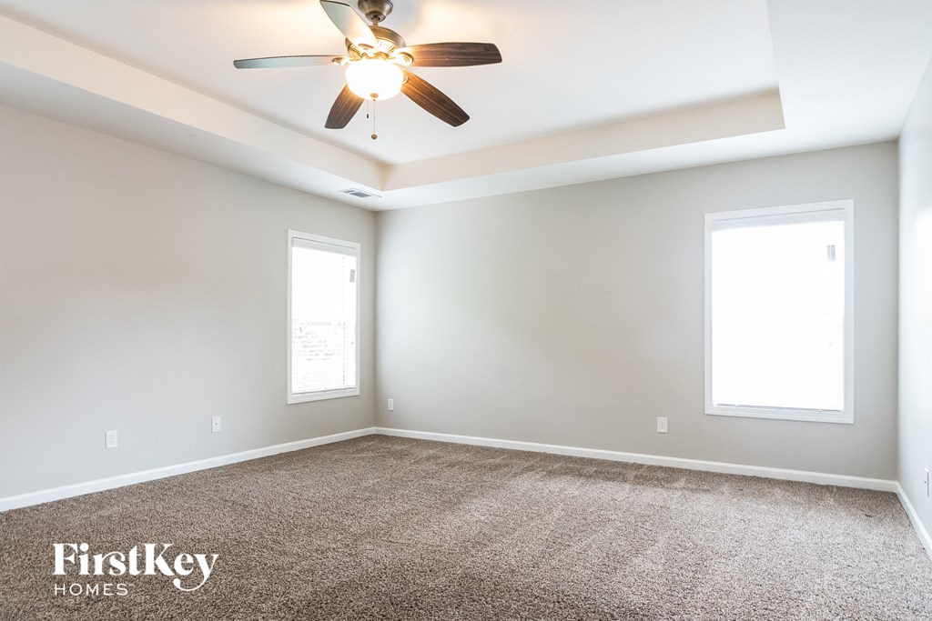 an empty room with a ceiling fan and two windows