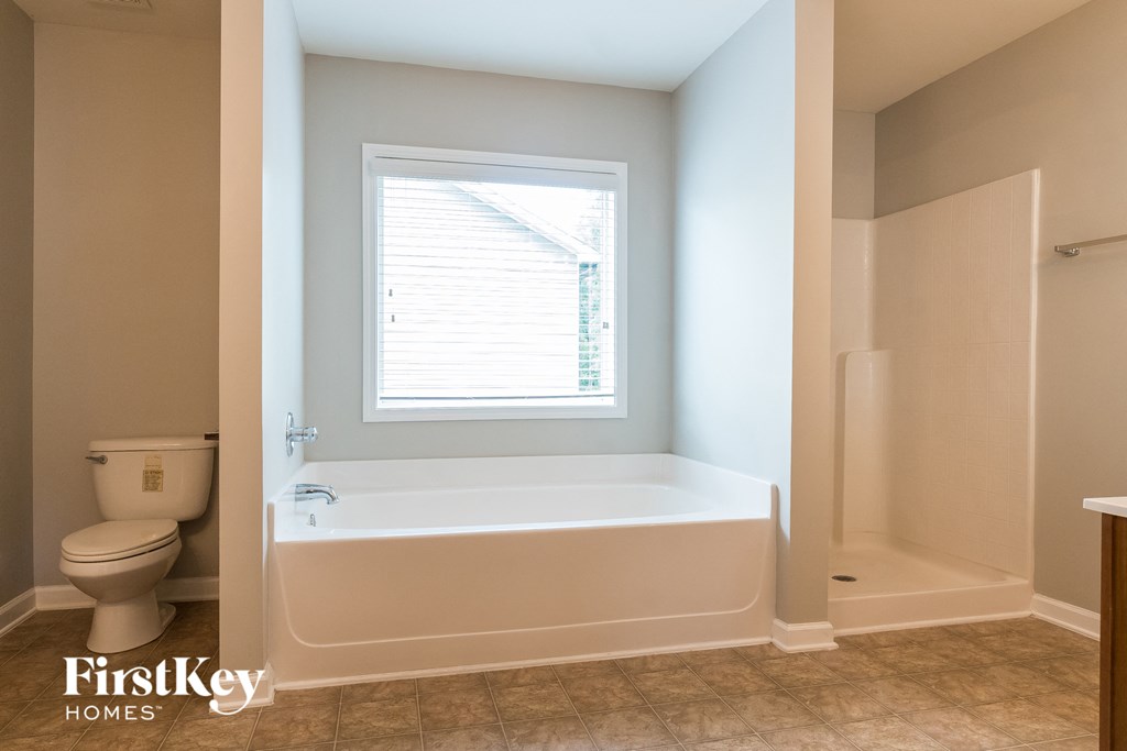 a bathroom with a tub and a toilet and a window