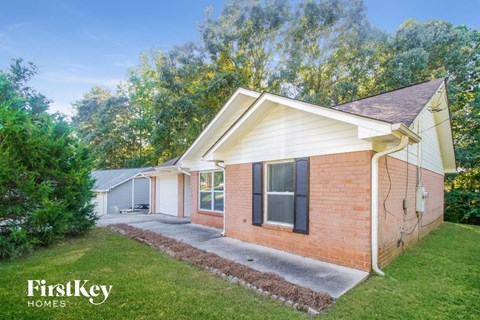 a small brick house with a yard and a driveway