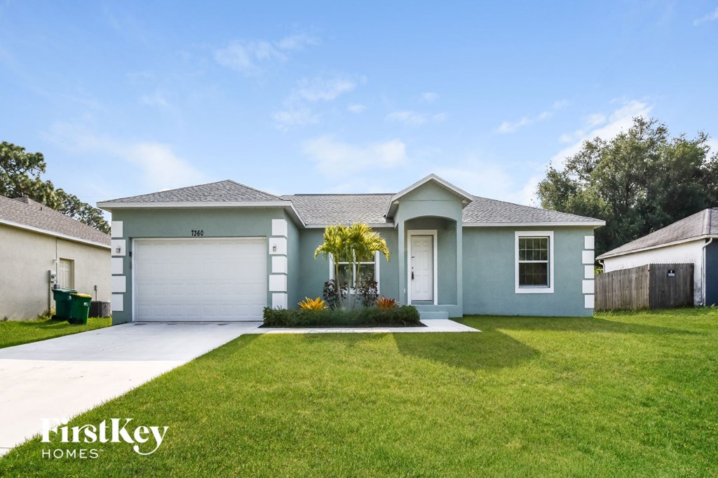 a blue house with a lawn and a garage