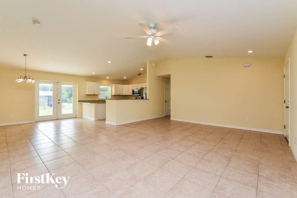 an empty living room and kitchen with a ceiling fan