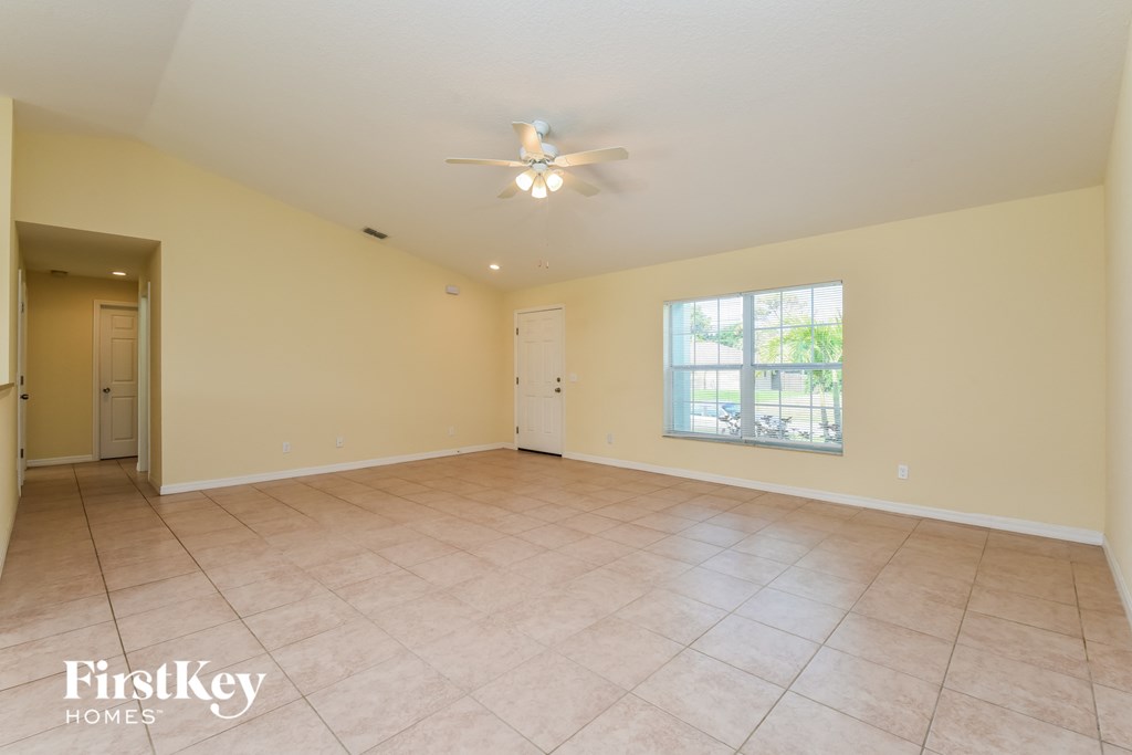 an empty living room with a ceiling fan and a window