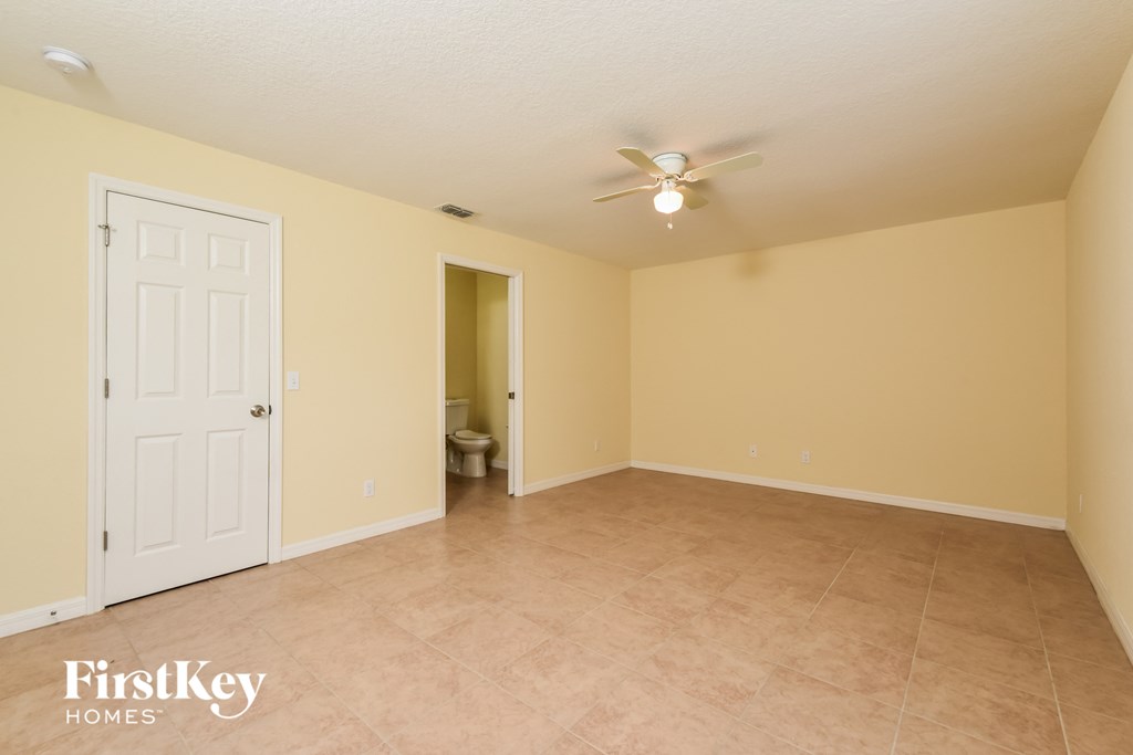 a spacious living room with beige walls and a ceiling fan