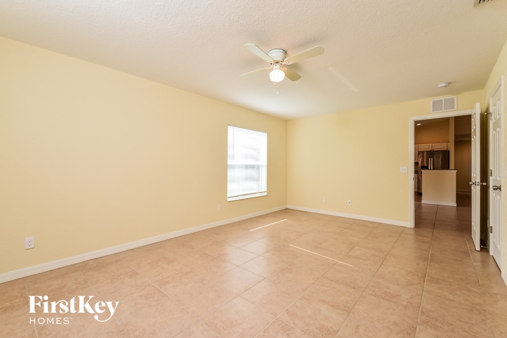 a spacious living room with beige walls and a ceiling fan