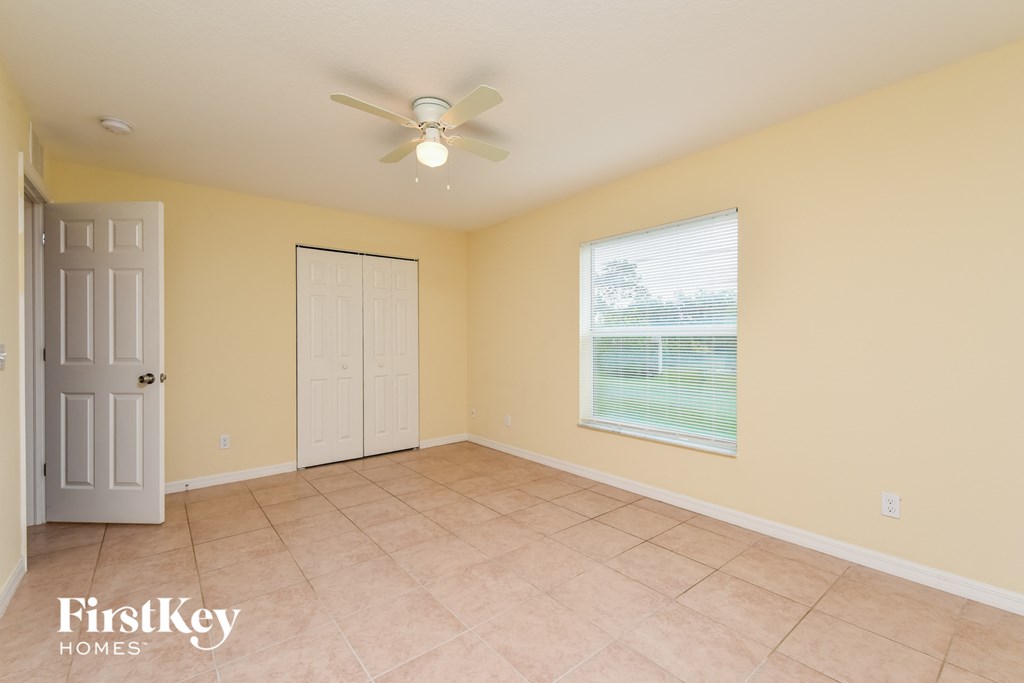 an empty living room with a ceiling fan and a door