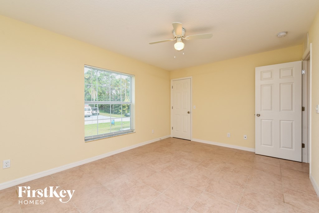 a spacious living room with a ceiling fan and a large window