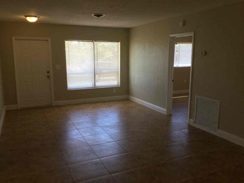 A room with tile flooring and two windows.