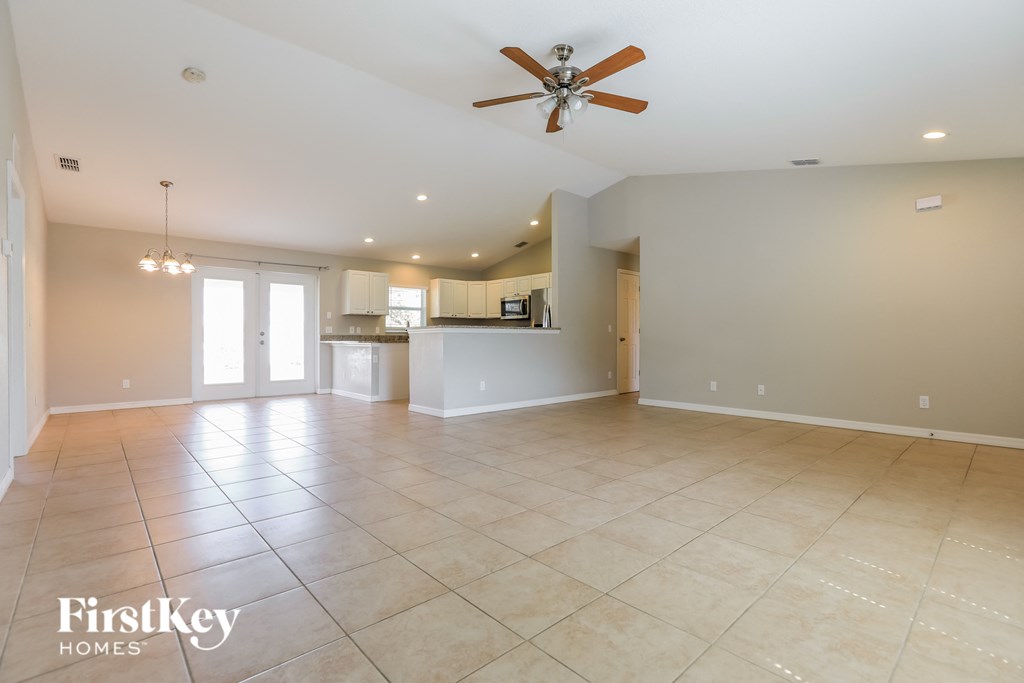 an empty living room and kitchen with a ceiling fan