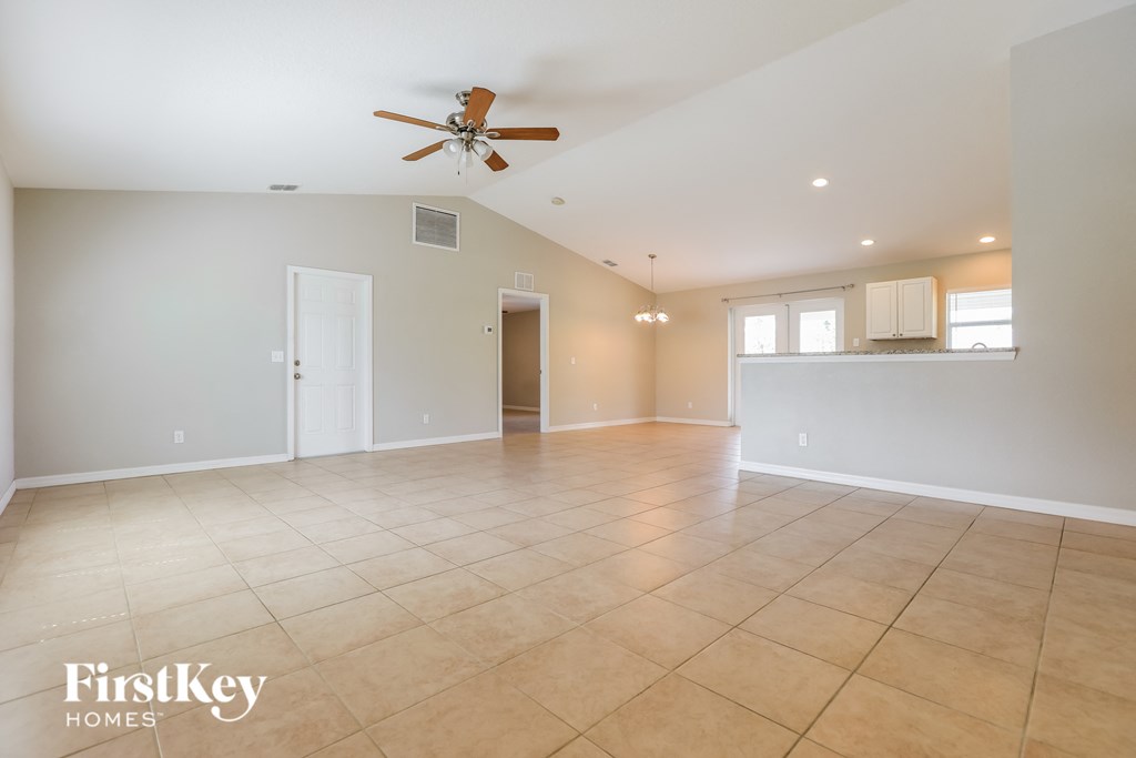 an empty living room with a ceiling fan and tiled floors