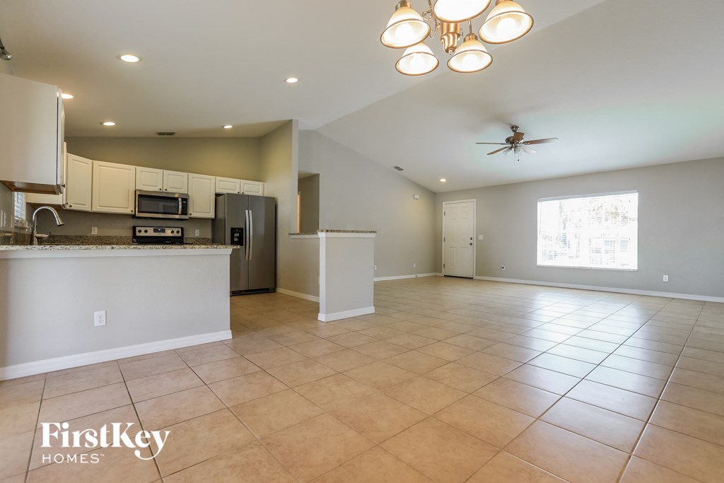 an open kitchen and living room with tile flooring and a ceiling fan