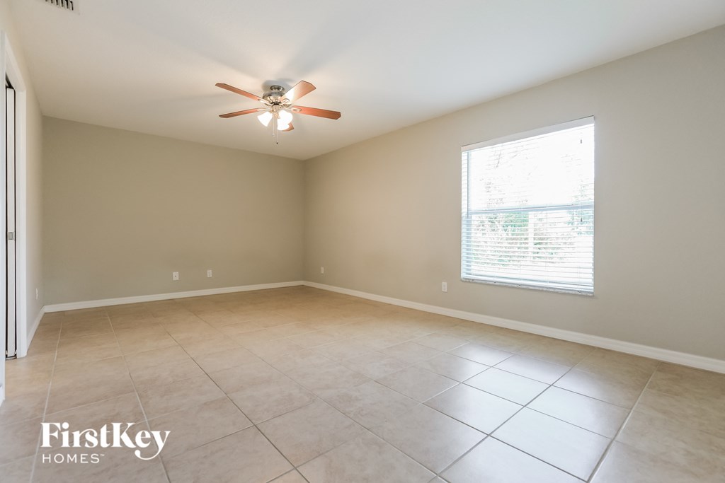 an empty living room with a ceiling fan and a window