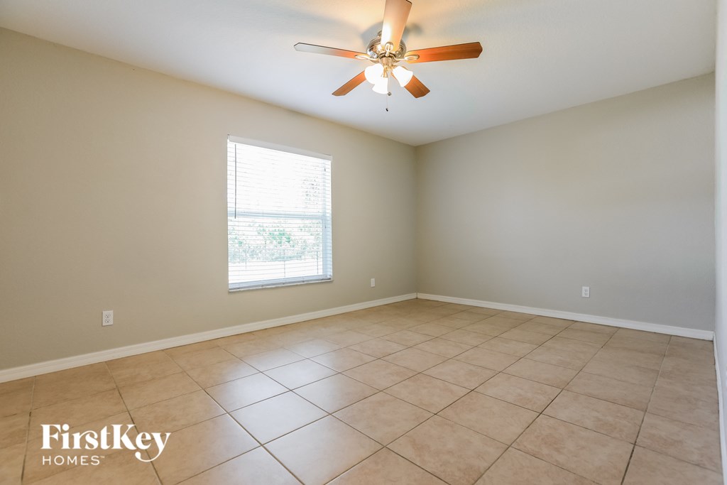 an empty living room with a ceiling fan and tiled floors