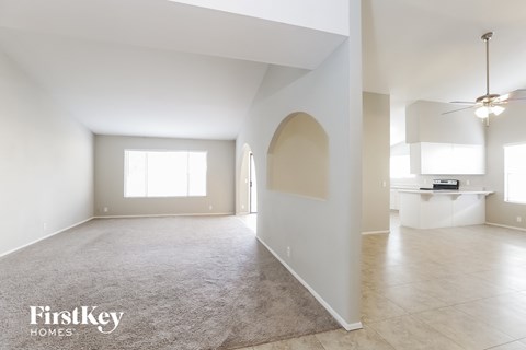 A spacious, empty room with a rug on the floor and a ceiling fan.