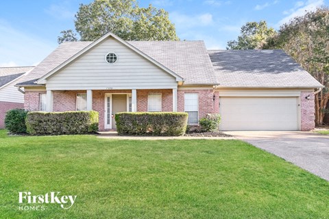 a white and brick house with a lawn in front of it