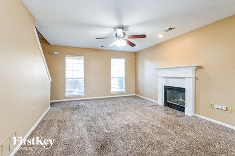 an empty living room with a fireplace and a ceiling fan