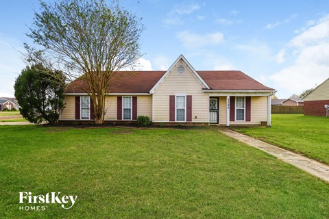 front view of a white house with red shutters and a green lawn