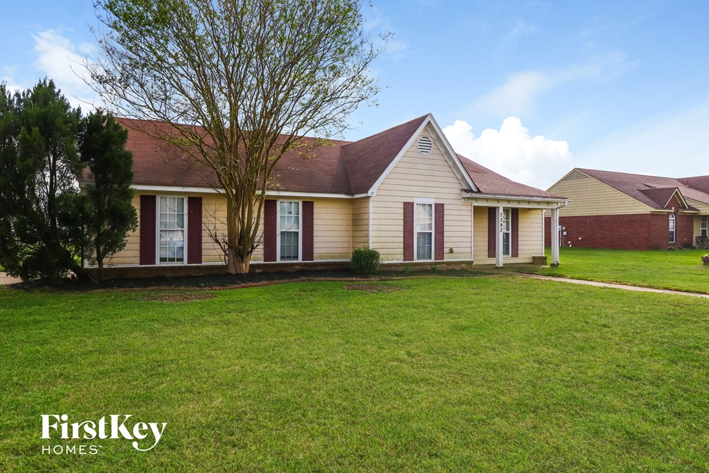 the front of a house with a lawn and a tree