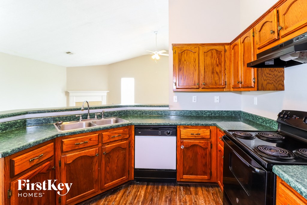 a kitchen with wood cabinets and black appliances and green counter tops