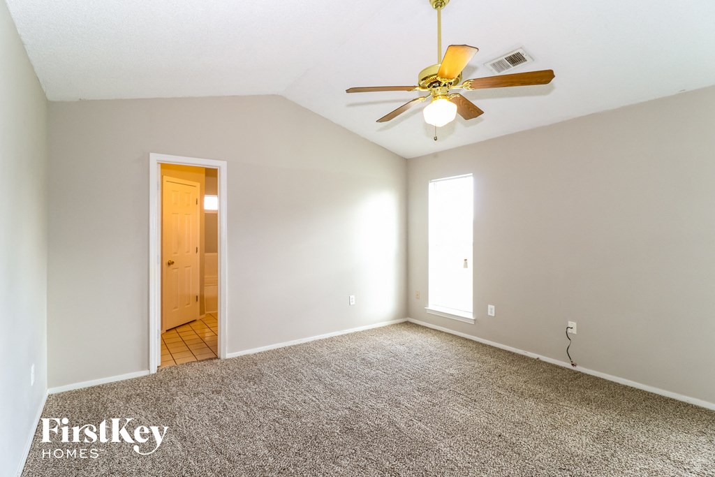 a living room with a ceiling fan and a carpet