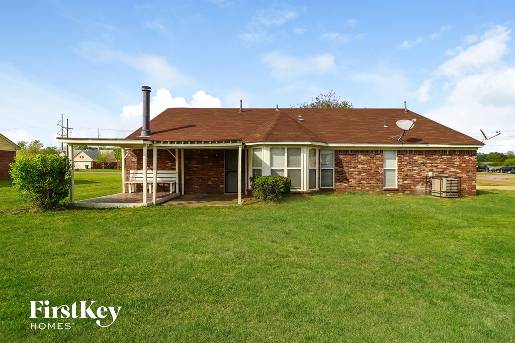 the front of a brick house with a lawn and a porch