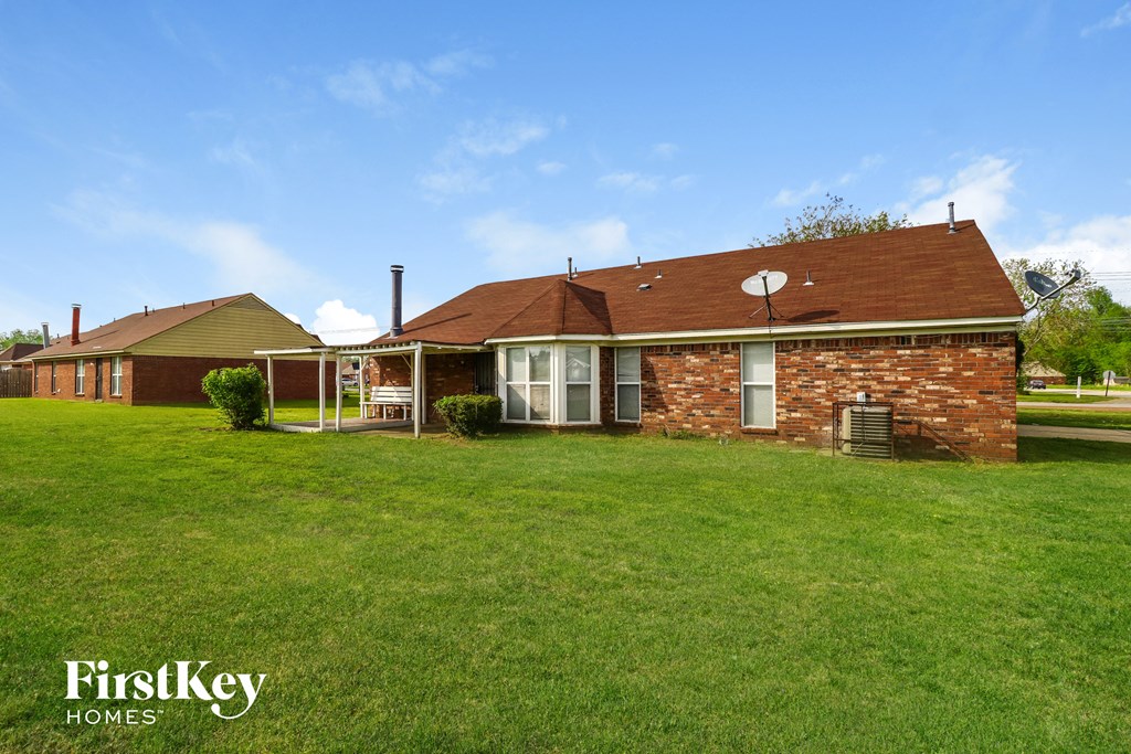 a brick house with a green lawn and a blue sky