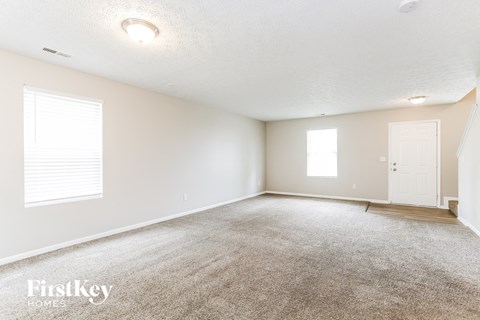 A spacious room with a carpeted floor and a door on the right side.