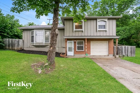 a small gray house with a yard and a tree