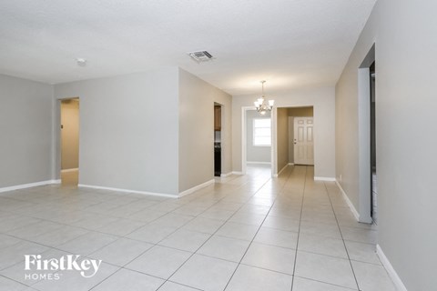 the living room and hallway of an empty house with white tile floors and white walls