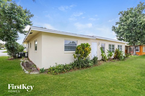a small white house with a yard and a lawn