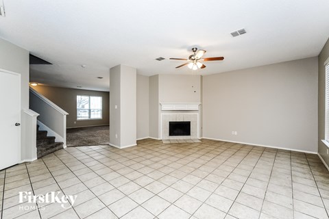 an empty living room with a fireplace and a ceiling fan
