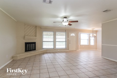 an empty living room with a ceiling fan and a fireplace