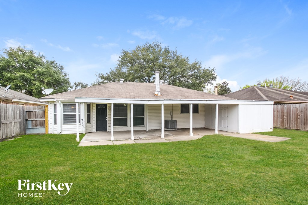 a small white house with a lawn and a fence