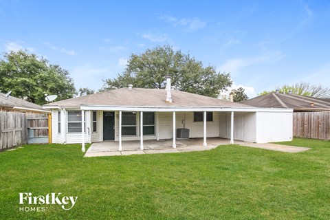 a small white house with a lawn and a fence