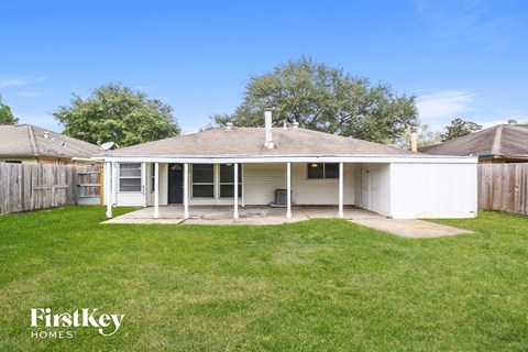 the backyard of a white house with a lawn and a fence