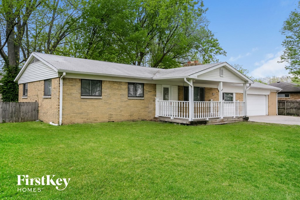 a brick house with a white porch and a grassy yard
