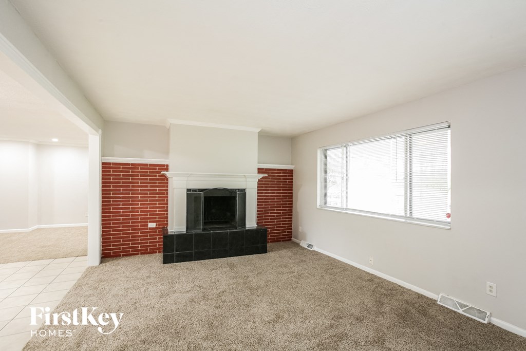 a living room with a brick fireplace and a window