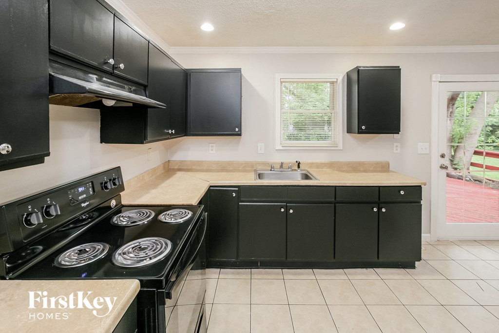 a kitchen with black cabinets and a stove and a sink