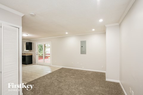 a spacious living room with carpet and a door to a kitchen