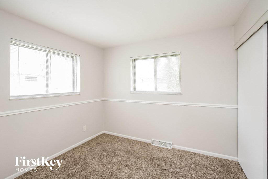 a bedroom with a carpeted floor and two windows
