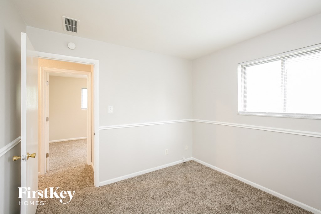 a bedroom with white walls and carpet and a window